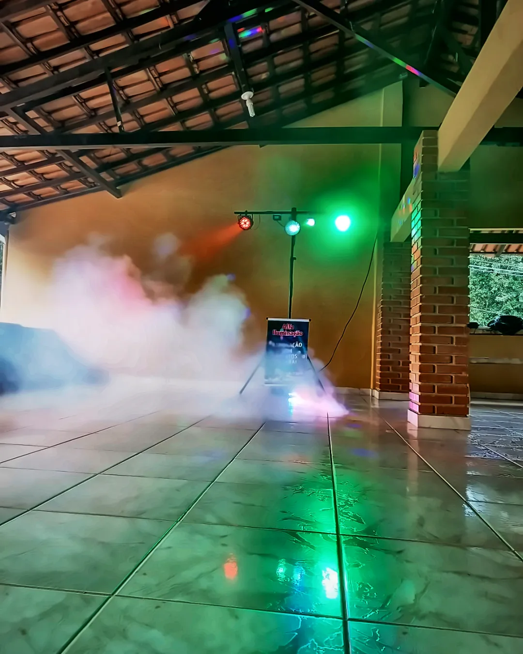 Salão com estrutura de luz montada e fumaça baixa no piso
